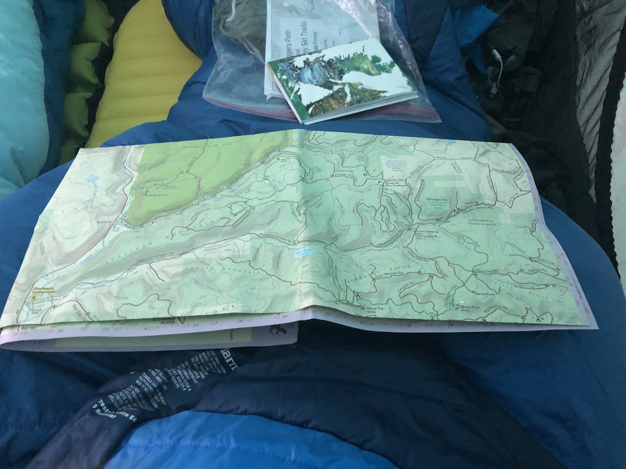 Photo of map and guide book on a sleeping bag