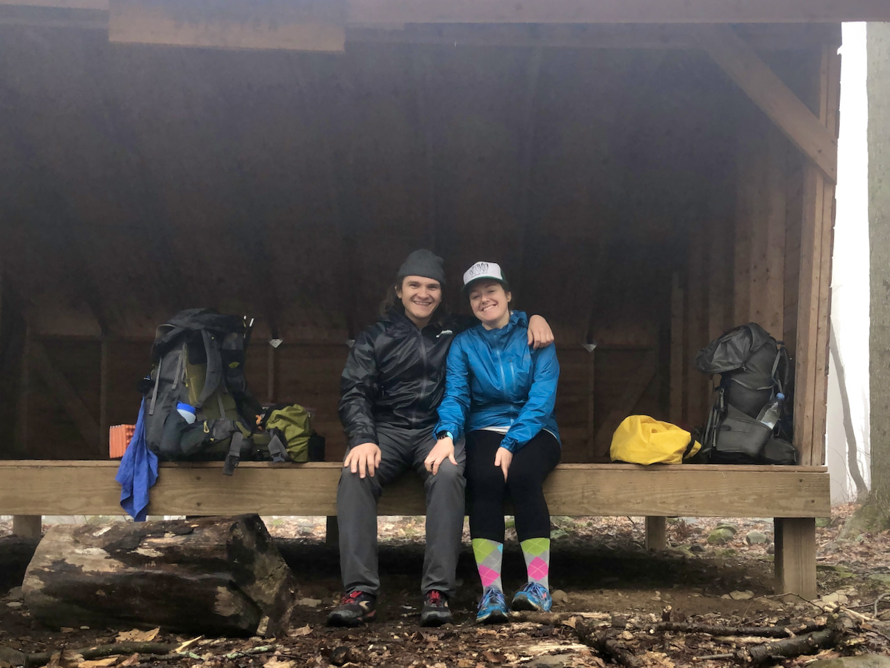 Photo of Brett and Becky at the Sprout Point Shelter surrounded by backpacks